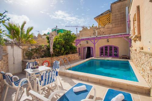 een villa met een zwembad en een tafel en stoelen bij Gozitan Farmhouse with Pool - PP 1 in Il-Wilġa
