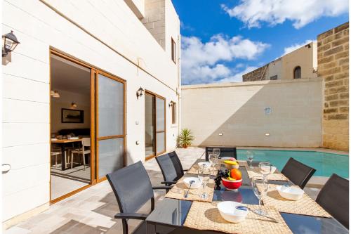 un patio con tavolo e sedie accanto alla piscina di Nadurija, So Nice Gozitan Villa + Pool - Happy Rentals a Nadur