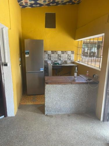 cocina con nevera de acero inoxidable en una pared amarilla en KEUR Junior, en Ndangane