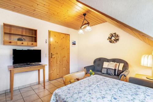 a living room with a bed and a television and a table at Vogtshof in Bad Rippoldsau-Schapbach