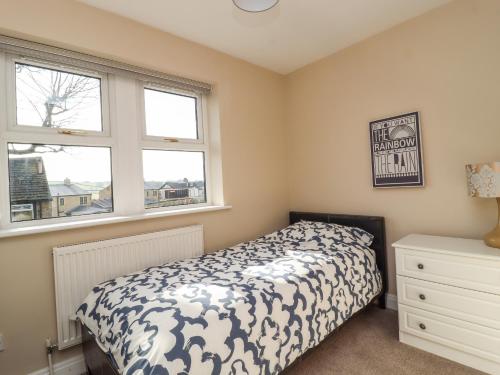 a bedroom with a bed and two windows at 5 Emmott Court in Colne