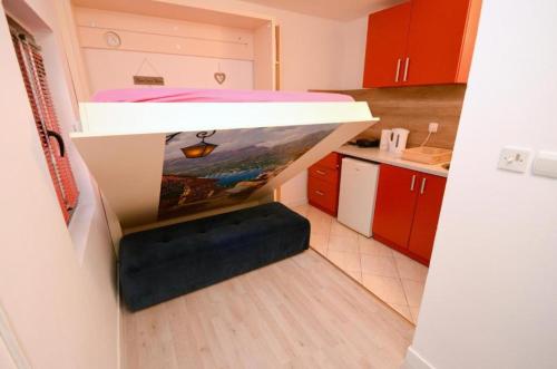 Majka 2 Apartments في كوتور: غرفة صغيرة بسرير في وسط مطبخ
