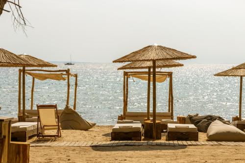 einen Strand mit Stühlen und Sonnenschirmen und dem Wasser in der Unterkunft Ergon Beach House Nikiti in Nikiti