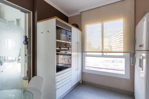une cuisine avec des placards blancs et une fenêtre dans l'établissement Stay Barcelona Long Term Camp Nou, à Barcelone