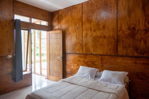 - une chambre avec un lit et un mur en bois dans l'établissement Rinjani Eco Villa, à Bayan