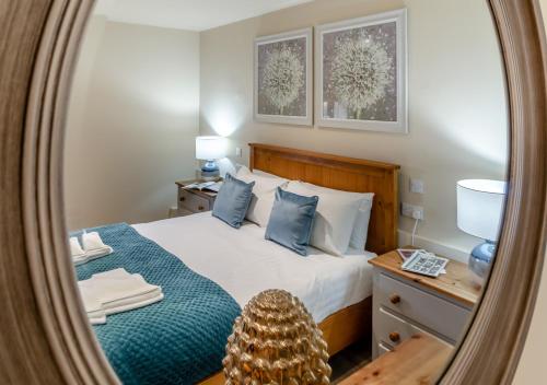 a bedroom with a bed with blue pillows and a mirror at White House Lodges - Wagtail in Heveningham