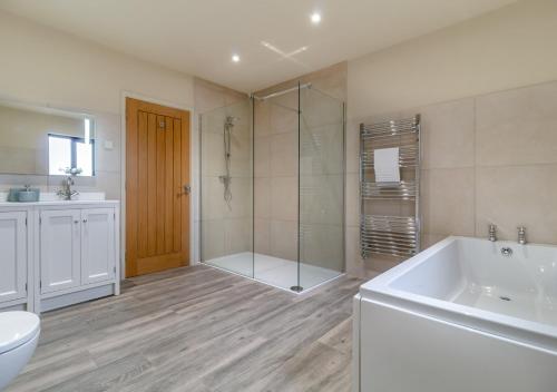 a bathroom with a shower and a tub and a sink at White House Lodges - Wagtail in Heveningham