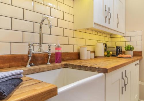 a kitchen with a sink in a kitchen with white cabinets at White House Lodges - Tawny in Heveningham