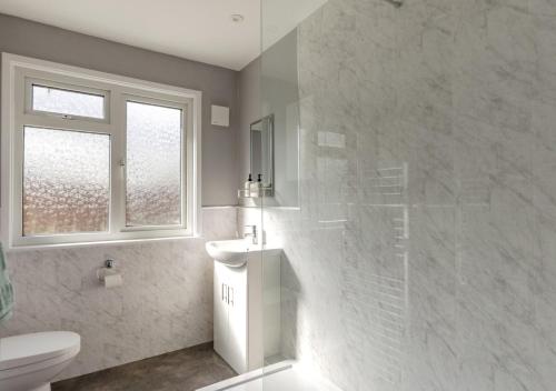 bagno con servizi igienici, lavandino e finestra di Cherry Trees - Acton a Waldingfield