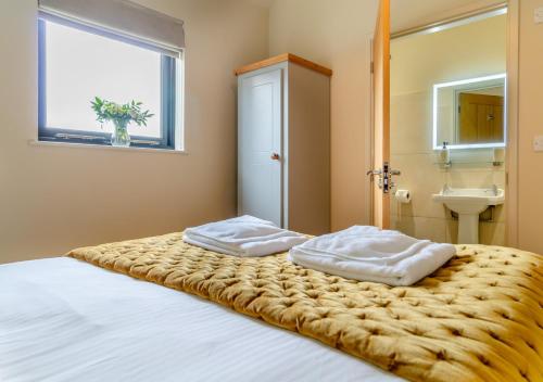 a bedroom with a bed with two pillows on it at White House Lodges - Avocet in Heveningham