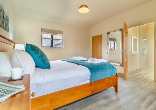 a bedroom with a large bed with blue pillows at White House Lodges - Avocet in Heveningham