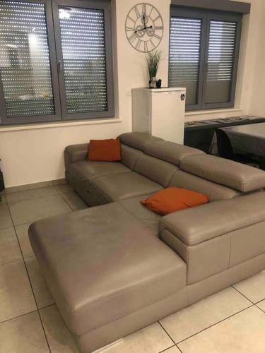 - un salon avec un canapé gris et des oreillers orange dans l'établissement Les Cotonnades (Colmar), à Wintzenheim