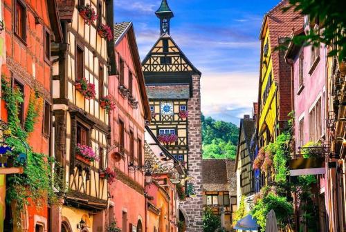 une rue de la ville avec des bâtiments et une tour de l'horloge dans l'établissement Les Cotonnades (Colmar), à Wintzenheim