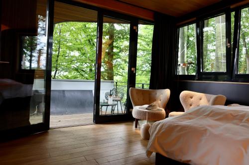 - une chambre avec un lit, des chaises et des fenêtres dans l'établissement K1 Baumhaus, à Odenthal