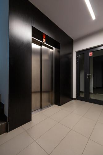 an elevator lobby with black walls and white tile floors at Apartamenty City Tower od WroclawApartament-pl in Wrocław