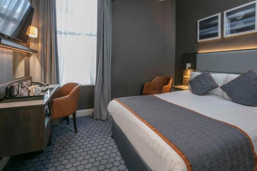 a hotel room with a bed and a desk at Best Western Plus Vauxhall Hotel in London