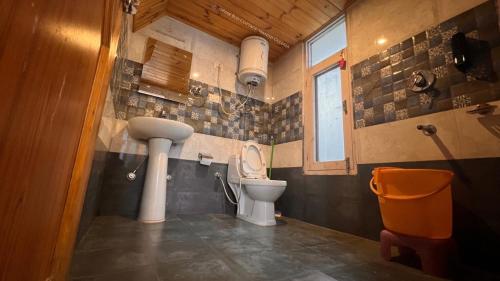 a bathroom with a toilet and a sink at Villa Pink Bud 6BHK in Manāli