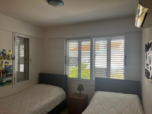a bedroom with two beds and two windows at SUNNY COAST in Paralimni