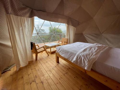a bedroom with a bed and a large window at L.T NATURE GLAMPS in Kodaikānāl