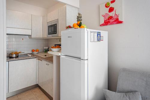 une cuisine avec un réfrigérateur blanc avec des fruits dessus dans l'établissement Eden Palace 3 - Happy Rentals, à Menton