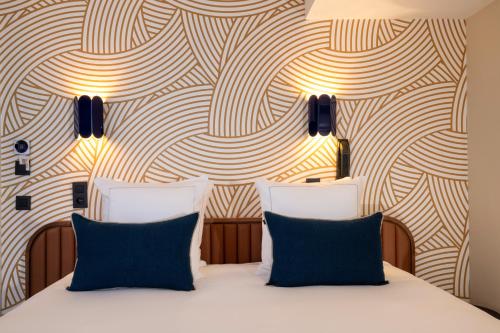 a bedroom with a bed with two blue pillows at Bijou Hôtel Paris Boulogne in Boulogne-Billancourt