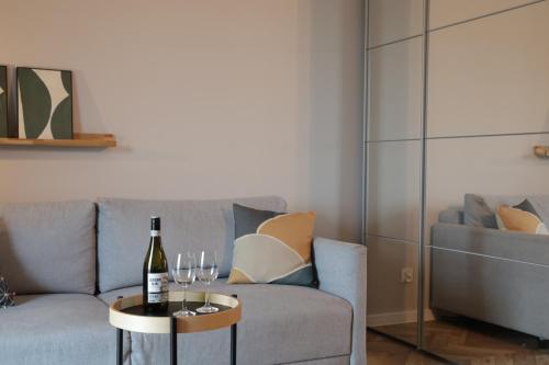 een woonkamer met een bank en een tafel met wijnglazen bij Capital Towers Prime in Rzeszów