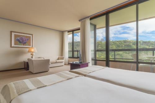 a bedroom with a large bed and large windows at Pestana Bahia Praia Nature & Beach Resort in Vila Franca do Campo