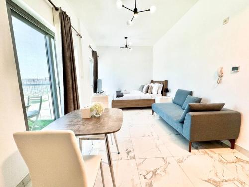 Mag 5 Spacious studio apartment في دبي: غرفة معيشة مع أريكة زرقاء وطاولة