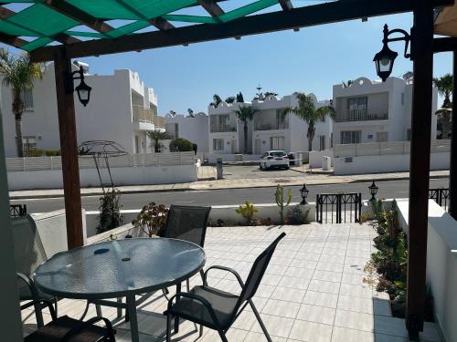 a patio with a glass table and chairs and buildings at SUNNY COAST in Paralimni