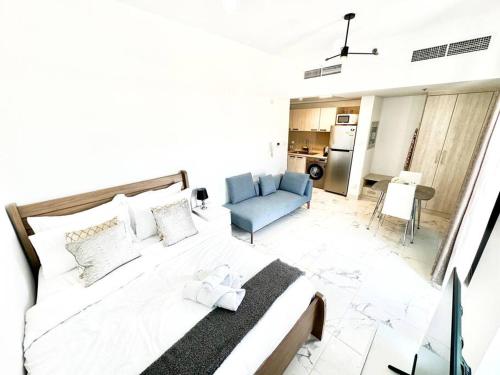 um quarto com uma grande cama branca e um sofá azul em Mag 5 Spacious studio apartment em Dubai