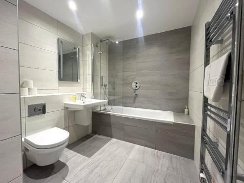 a bathroom with a toilet and a sink and a tub at Harbourside Haven - One Bed Apartment with Balcony in Bristol