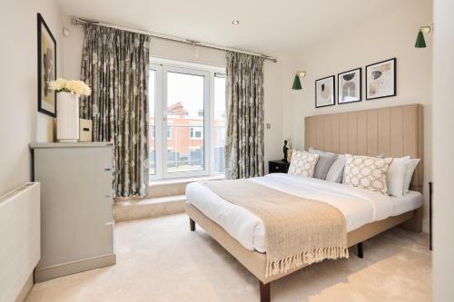um quarto com uma cama grande e uma janela em The Battersea Park Place - Amazing 2BDR Flat with Terrace em Londres