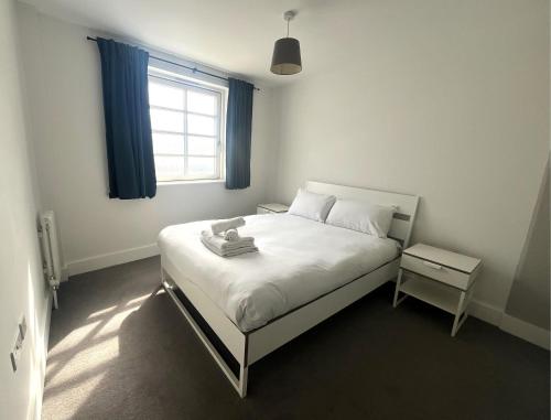 a bedroom with a white bed and a window at Harbourside Haven - One Bed Apartment with Balcony in Bristol