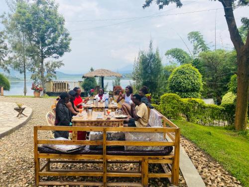 a group of people sitting at a wooden table at Ruhondo Beach Resort in Ruhengeri