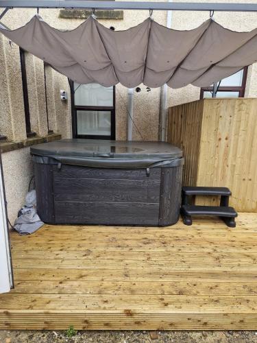 a black tub sitting on a wooden floor with a canopy at The M Rooms at 144 in Kirk of Shotts