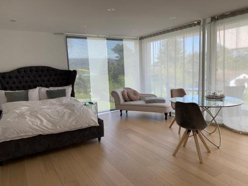 een slaapkamer met een bed, een tafel en een stoel bij Deluxe Doppelzimmer mit Pool und Aussicht in Dänikon