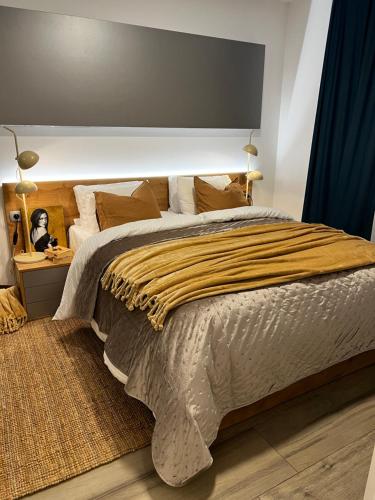 a bedroom with a large bed with a yellow blanket at LuxArt City Spa Gallery Residence Krk in Krk