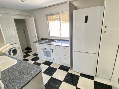 uma cozinha com um frigorífico branco e um piso em xadrez em Tor Serena-Fincas Benidorm em Benidorm