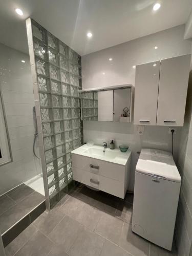une salle de bain blanche avec un lavabo et une douche dans l'établissement Le Bennett, T2 central à 200 mètres des plages, à Menton
