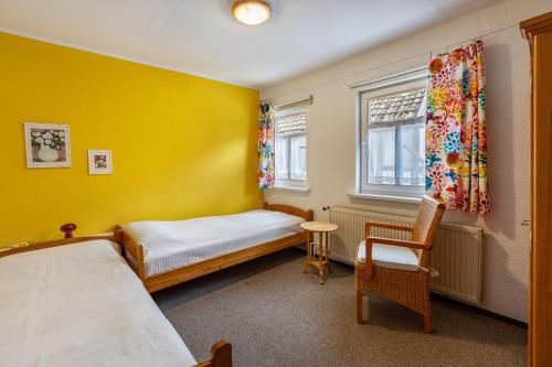 a bedroom with yellow walls and a bed and a chair at Ferienhaus Bodebaude in Thale