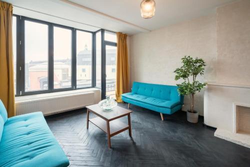 een woonkamer met een blauwe bank en een tafel bij Charming and Spacious Apartments in the Heart of Antwerp in Antwerpen