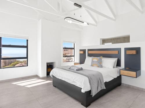 1 dormitorio con 1 cama grande, paredes y ventanas blancas en Blueberry Villa by Host Agents, en St Helena Bay