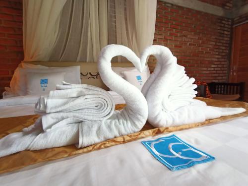 two swans towels sitting on top of a bed at Coco Garden Pool Villas in Kubutambahan