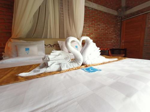 two swans made out of towels sitting on a bed at Coco Garden Pool Villas in Kubutambahan