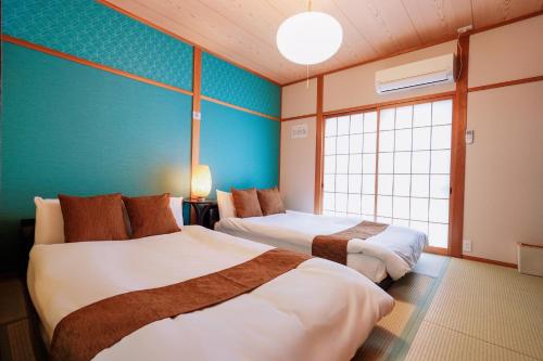 um quarto de hotel com duas camas e uma janela em USJ直达，2站5分钟!Meeno home西九条·美の宿亲子民宿· 马里奥手环有·大空间·出行便利 em Osaka