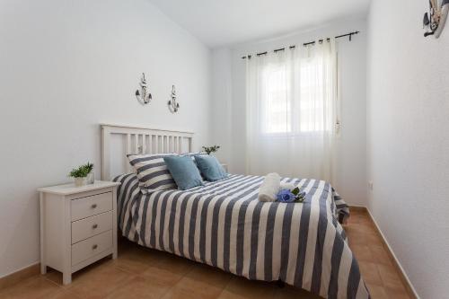 a bedroom with a bed with blue pillows and a window at Laguna 3 Rooms Piscina in Chipiona