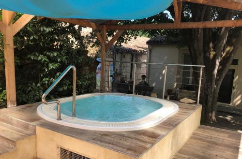 a hot tub in a deck with an umbrella at La Vie en Roses in Rennes-les-Bains