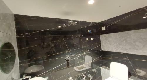 a black tiled bathroom with two sinks and two mirrors at Hotel Planet Villa in Ahmedabad