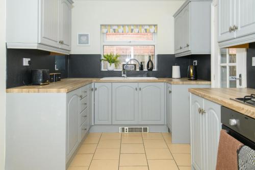 una cocina con armarios blancos y fregadero en Stylish 3 Bed House Near Hospital, Racecourse, Free Parking, 