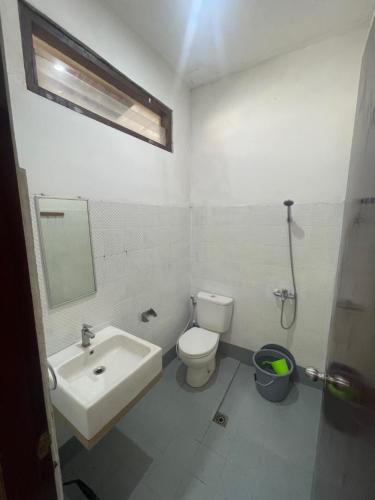 La salle de bains est pourvue de toilettes blanches et d'un lavabo. dans l'établissement Shaka House at alun alun kidul, à Timuran